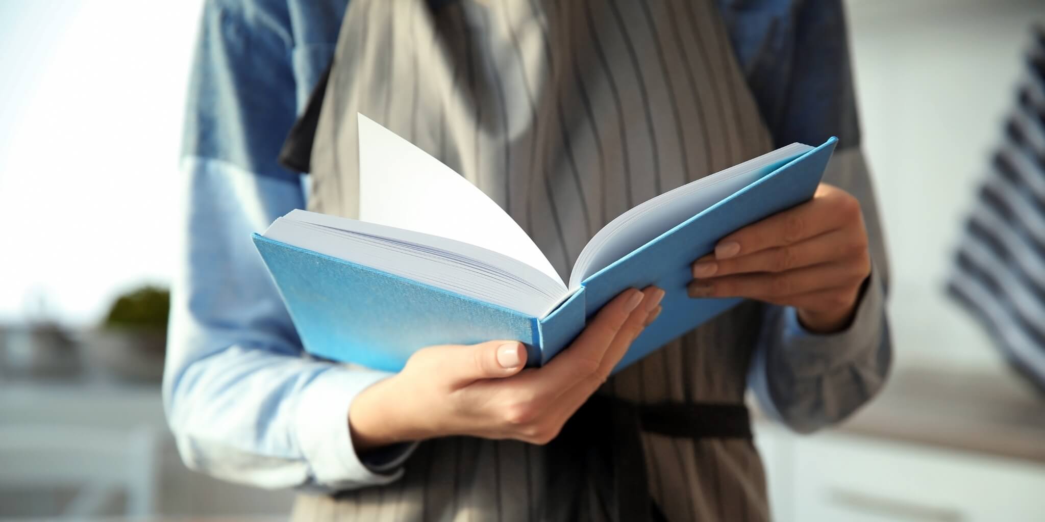 Woman wearing apron and reading recipe book.